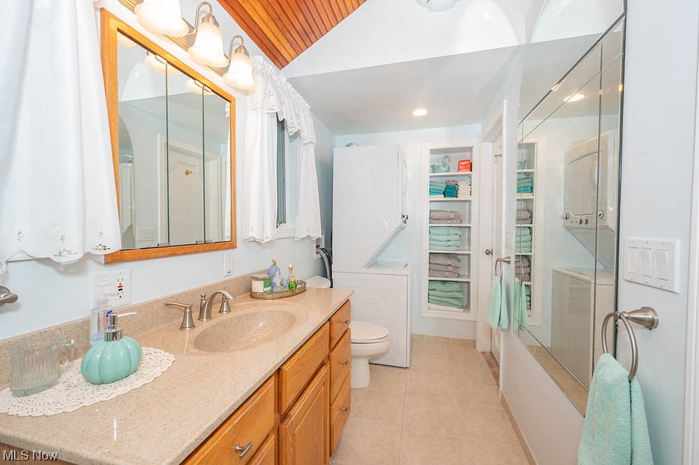 807 North Road Southeast Warren, OH 44484 - Photo 15 of 24 Full bathroom featuring shower / tub combination, tile flooring, toilet, stacked washer / drying machine, and vanity with extensive cabinet space