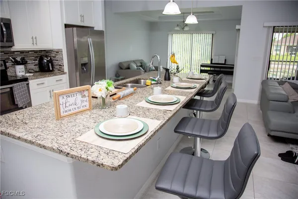 a kitchen with stainless steel appliances granite countertop a table chairs and a refrigerator