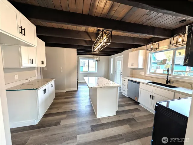 a living room with stainless steel appliances granite countertop furniture and a wooden floor