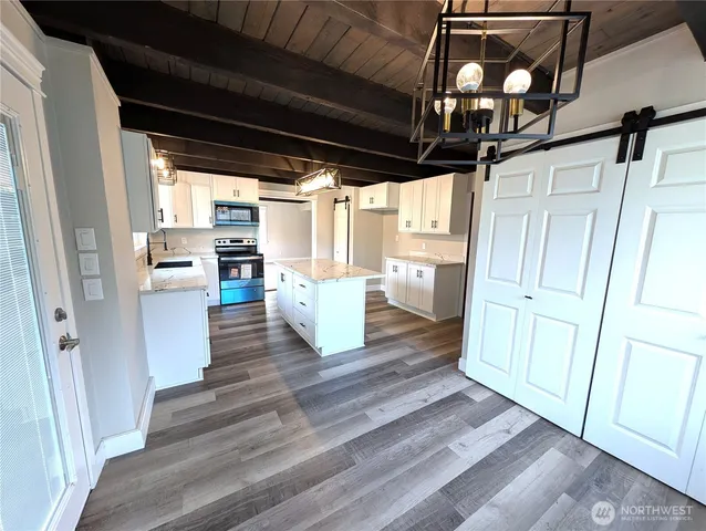 a kitchen with stainless steel appliances granite countertop a sink dishwasher a stove a refrigerator with wooden floors and cabinets