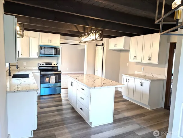 a large kitchen with kitchen island wooden floors and stainless steel appliances