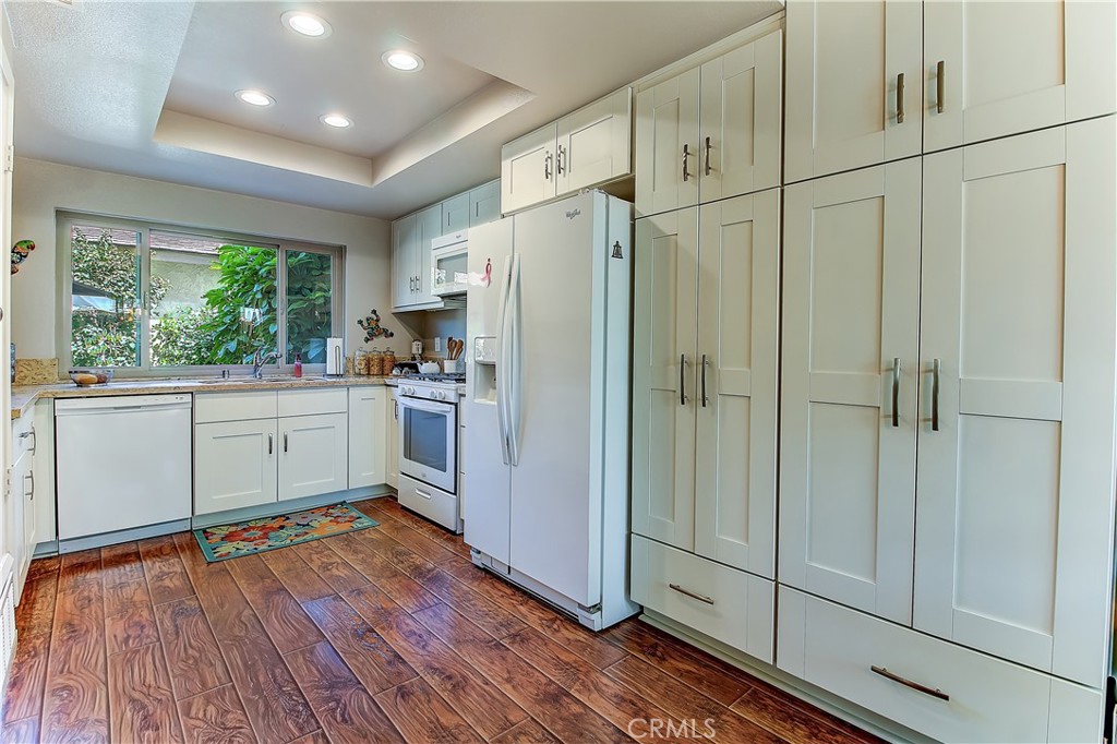 6618 Wintertree Drive Riverside, CA 92506 - Photo 16 of 37 a kitchen with granite countertop a refrigerator a sink and white cabinets