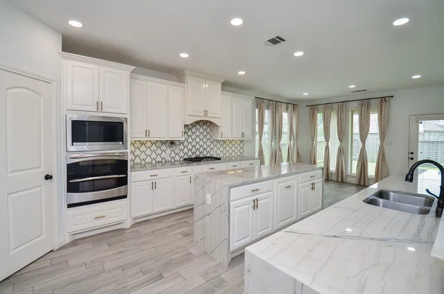 a large white kitchen with a large counter top appliances and cabinets