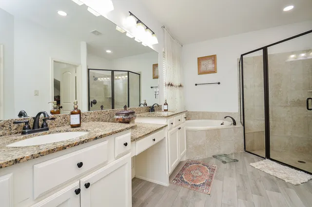 a bathroom with a granite countertop sink a large mirror and a bathtub