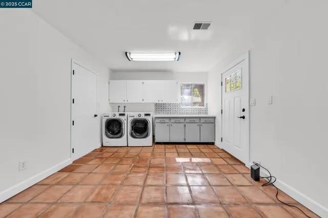 an empty room with wooden floor cabinet and windows