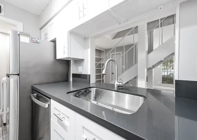 a kitchen with stainless steel appliances granite countertop a sink dishwasher and cabinets with wooden floor