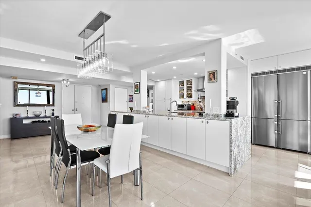 a kitchen with stainless steel appliances kitchen island granite countertop a table chairs and a refrigerator