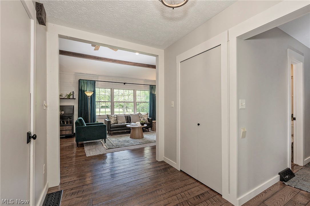 11292 Butternut Road Chardon, OH 44024 - Photo 7 of 49 Warm wood-finish flooring extends throughout the entry, featuring a bi-fold closet, leading into a living area with exposed beam accents, shiplap wall detailing, and abundant natural light from multiple windows