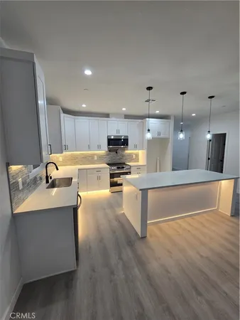 a kitchen with stainless steel appliances granite countertop a sink a stove and a refrigerator