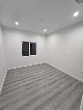 a view of an empty room with wooden floor and windows