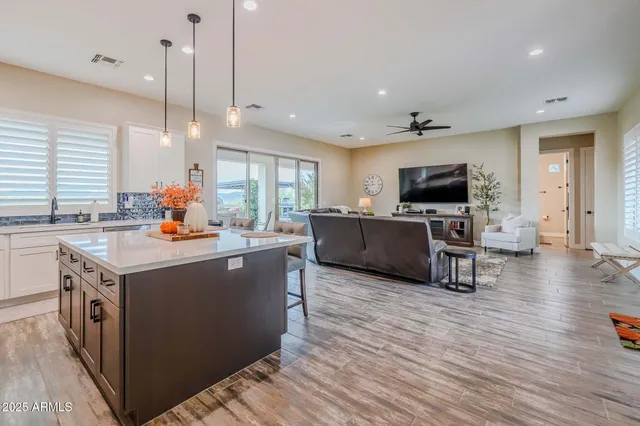 a view of a kitchen with kitchen island a counter top space a sink stainless steel appliances and cabinets