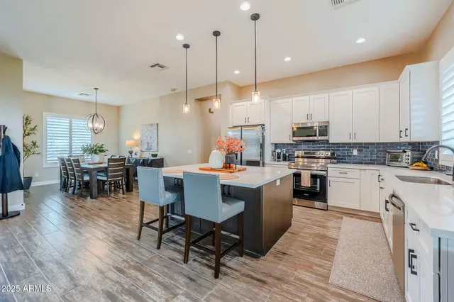 a kitchen with stainless steel appliances granite countertop wooden floors refrigerator and dining table