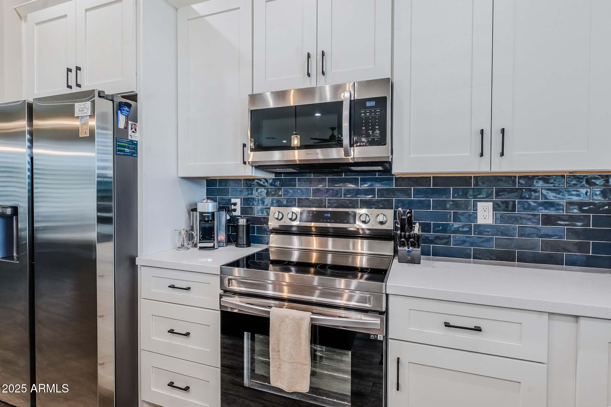 2049 East Gaffney Road New River, AZ 85087 - Photo 18 of 77 a kitchen with stainless steel appliances granite countertop a stove a refrigerator and a white cabinets