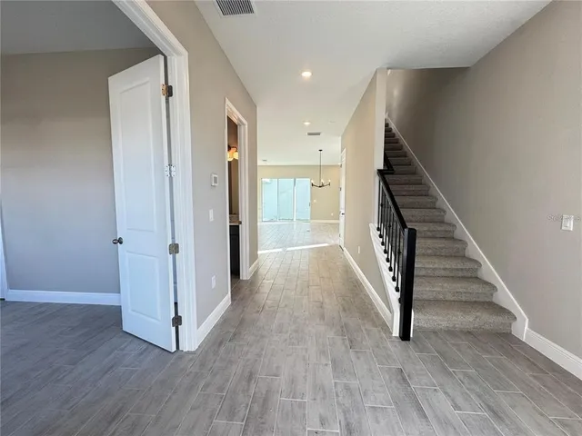 a view of a hallway with wooden floor and stairs