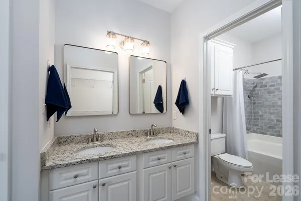 a en suite bathroom with a granite countertop sink and a mirror