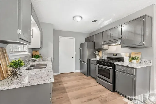 a kitchen with stainless steel appliances granite countertop a stove a sink and a refrigerator