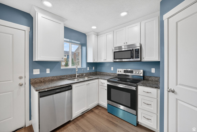 295 Spruce Way Santaquin, UT 84655 - Photo 10 of 32 Modern kitchen featuring white cabinetry, stainless steel appliances, granite-style countertops, and wood-finish flooring