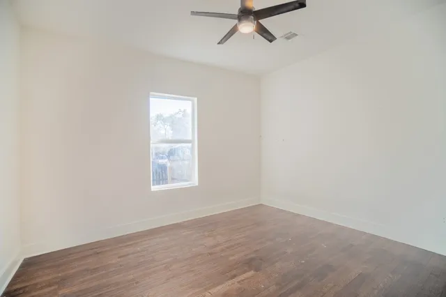 an empty room with a window and a fan