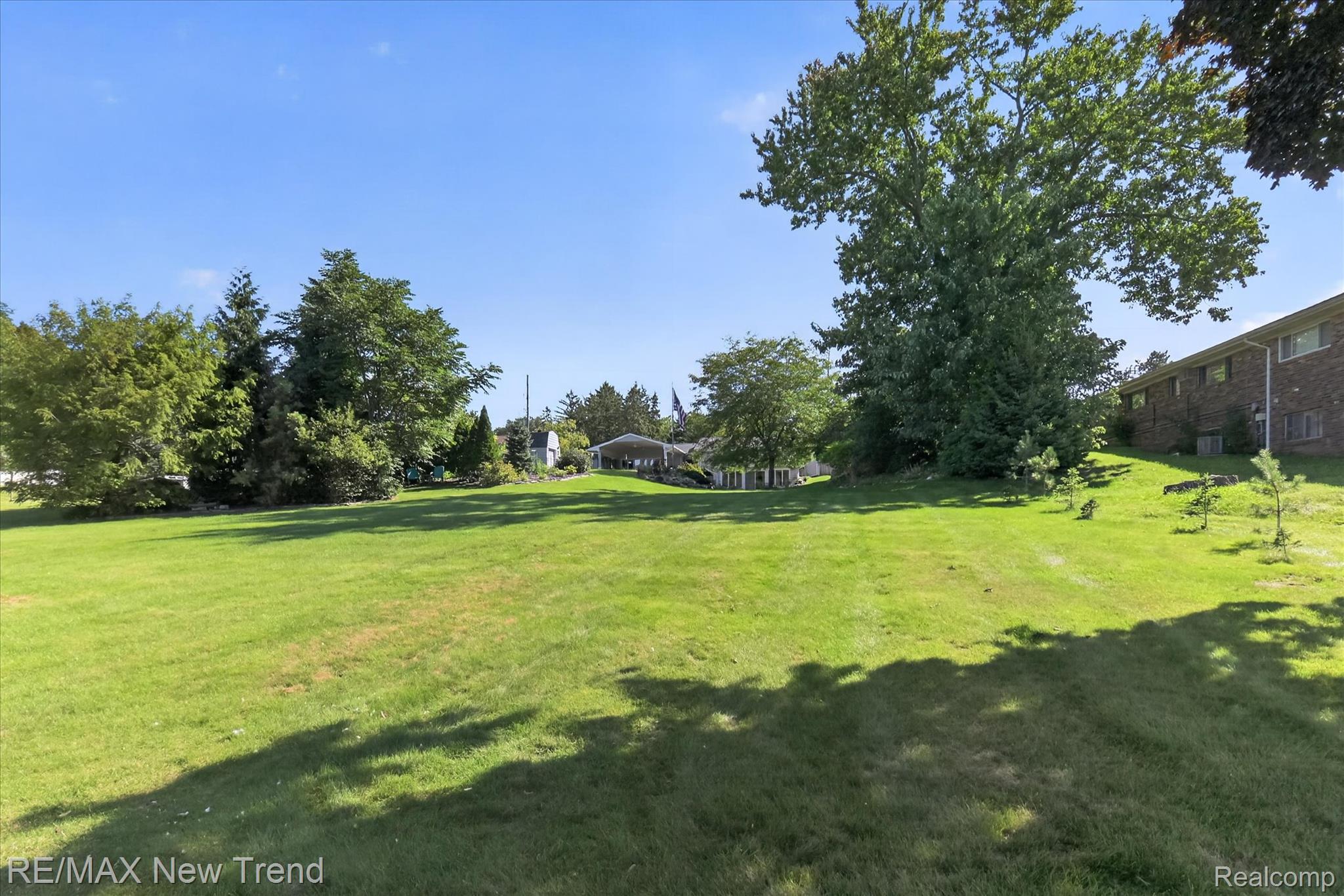 2529 South Commerce Road Walled Lake, MI 48390 - Photo 54 of 66 Expansive green lawn with mature trees and a distant structure featuring a covered patio