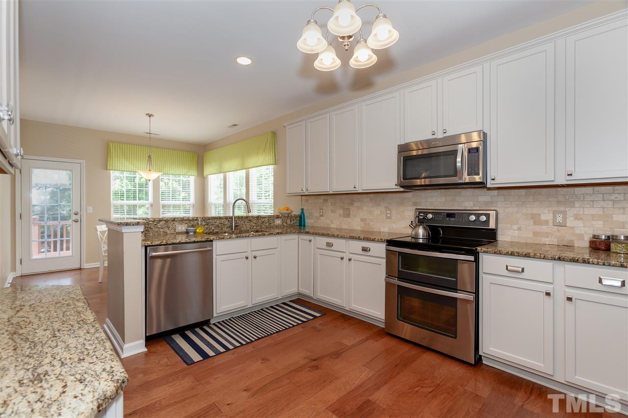 7331 Brandon Allen Avenue Raleigh, NC 27613 - Photo 5 of 25 Granite countertops, stainless appliances, professionally painted cabinets (doors were sprayed in workshop), and stone backsplash make this a kitchen you'll love spending time in. The kitchen flows into living room for easy conversation.
