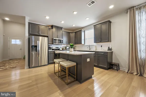 a kitchen with kitchen island a refrigerator a sink dishwasher with a fireplace and cabinets