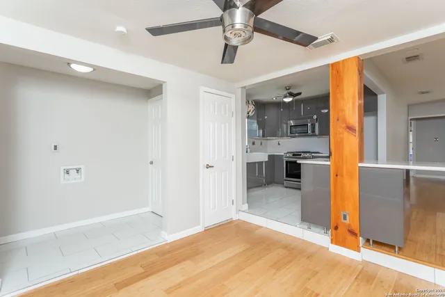 a view of a hallway with wooden floor and a kitchen