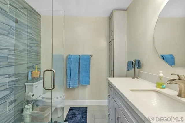 a bathroom with a granite countertop sink a toilet and shower