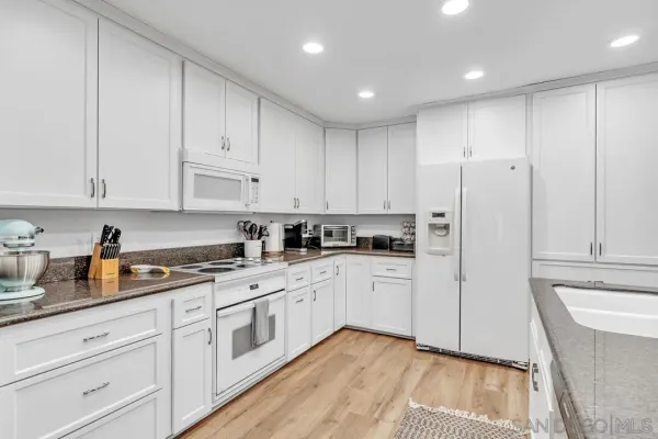 a kitchen with white cabinets white appliances and sink