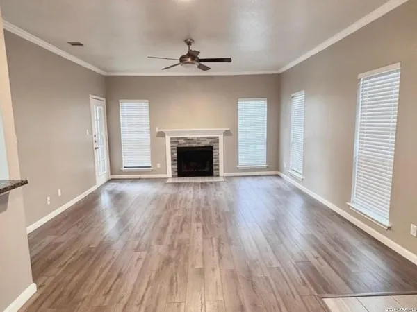 an empty room with wooden floor fireplace and windows