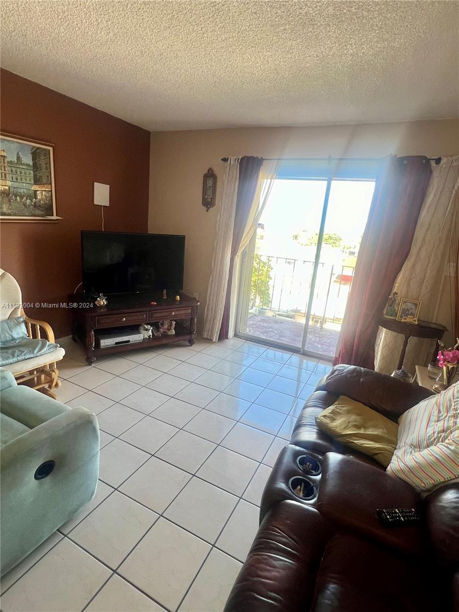 1075 West 68th Street, Unit 309 Hialeah, FL 33014 - Photo 11 of 21 a living room with furniture and a flat screen tv