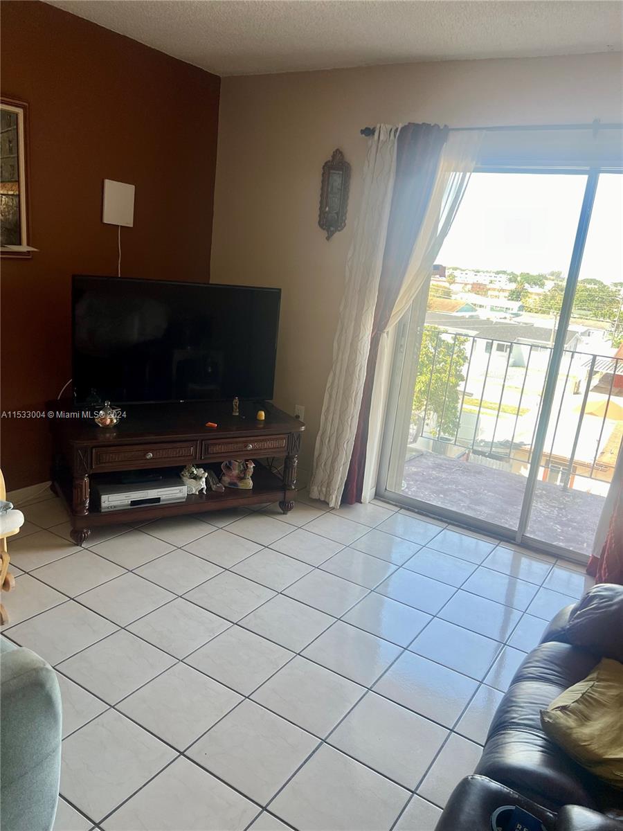 1075 West 68th Street, Unit 309 Hialeah, FL 33014 - Photo 12 of 21 a living room with furniture a flat screen tv and a window