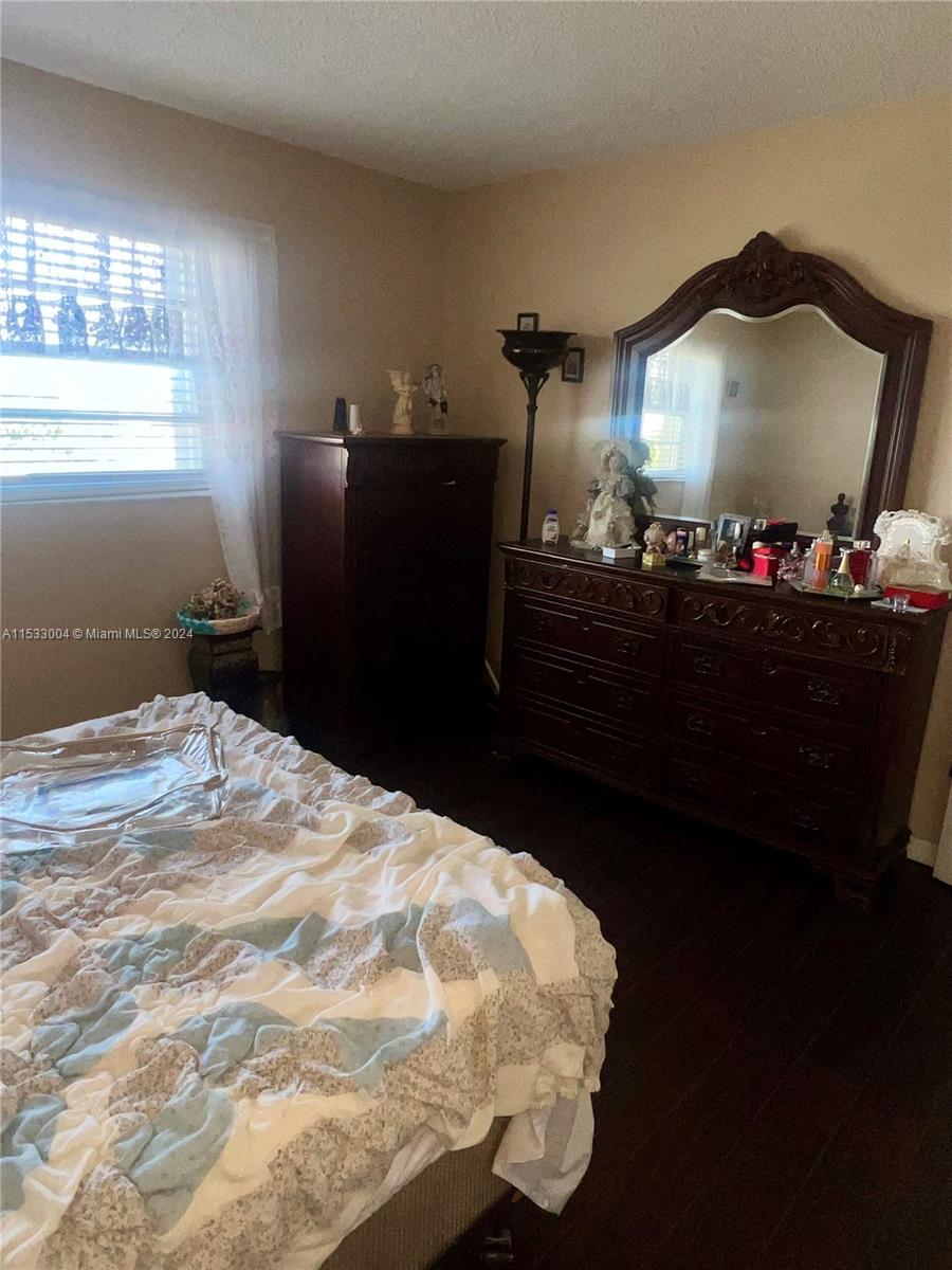 1075 West 68th Street, Unit 309 Hialeah, FL 33014 - Photo 20 of 21 a bed room with a bed dresser and a mirror