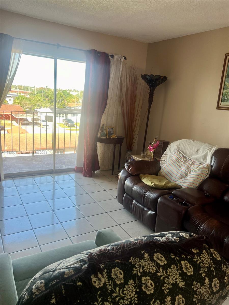 1075 West 68th Street, Unit 309 Hialeah, FL 33014 - Photo 9 of 21 a living room with furniture and a floor to ceiling window