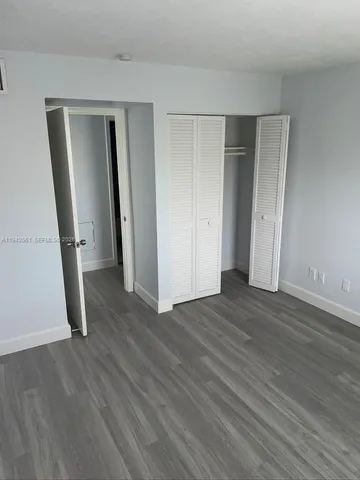 an empty room with wooden floor and mirror