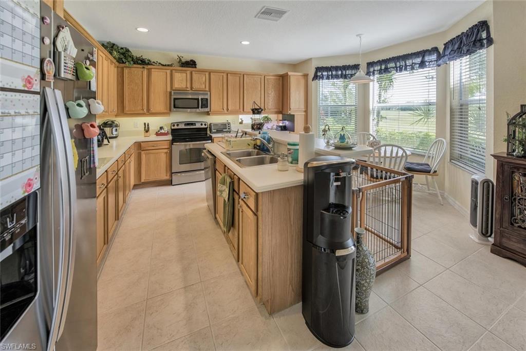 2084 Par Drive Naples, FL 34120 - Photo 11 of 29 a kitchen with stainless steel appliances granite countertop a refrigerator a stove a sink and a dining table with wooden floor