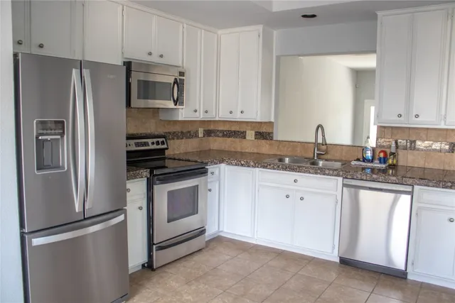 a kitchen with granite countertop white cabinets and stainless steel appliances