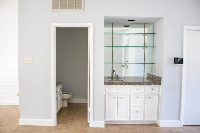 a bathroom with a granite countertop sink a toilet and mirror