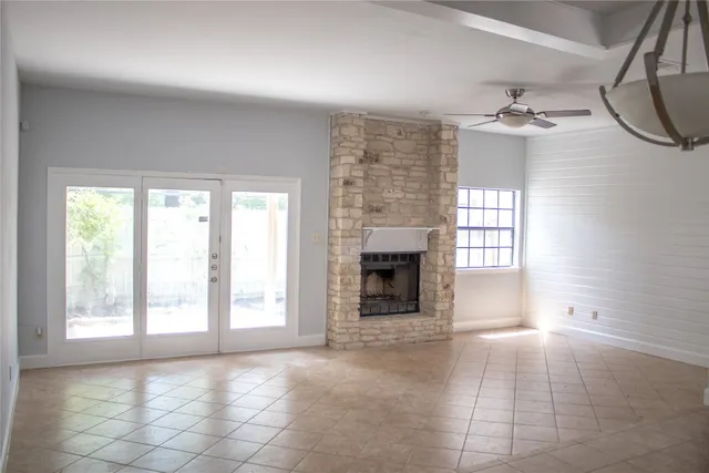 an empty room with windows and fireplace
