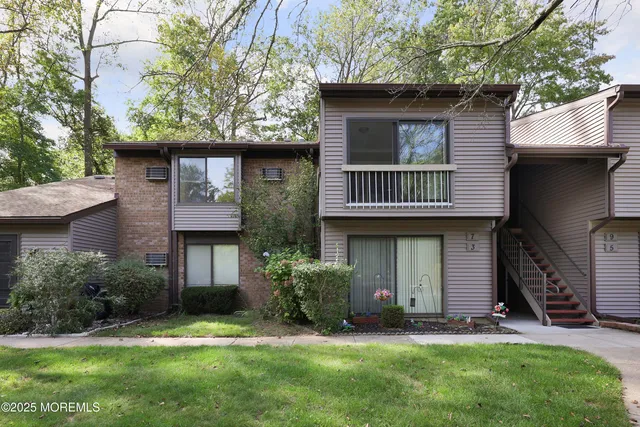 a view of a house with a yard and a large tree