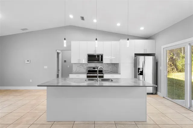 a large kitchen with stainless steel appliances a large counter top a stove and a refrigerator