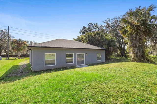 a house that is sitting in the grass with large trees