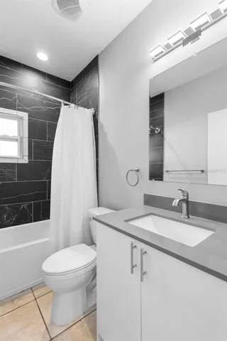 a bathroom with a sink a toilet a mirror and bathtub