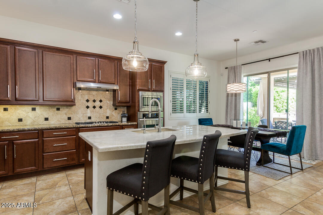 4647 North Aldea Road East Litchfield Park, AZ 85340 - Photo 15 of 49 a kitchen with granite countertop a table chairs sink and cabinets