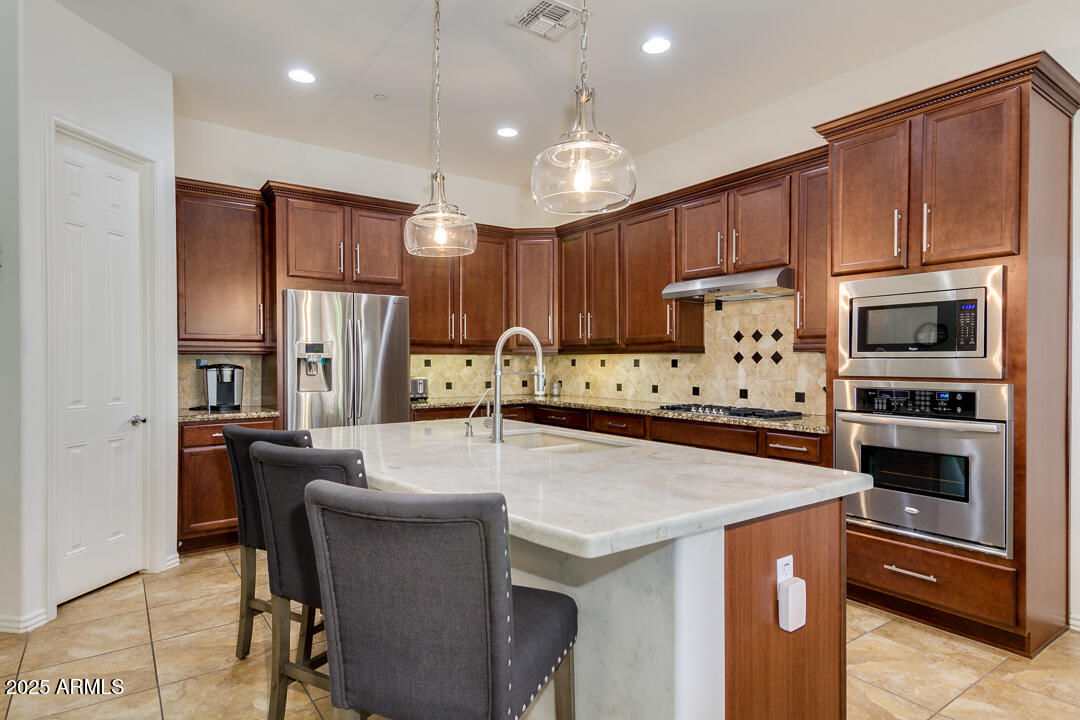 4647 North Aldea Road East Litchfield Park, AZ 85340 - Photo 16 of 49 a kitchen with granite countertop a stove refrigerator and microwave