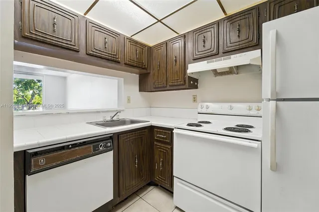 a kitchen with stainless steel appliances granite countertop white cabinets and a stove a refrigerator with wooden floors