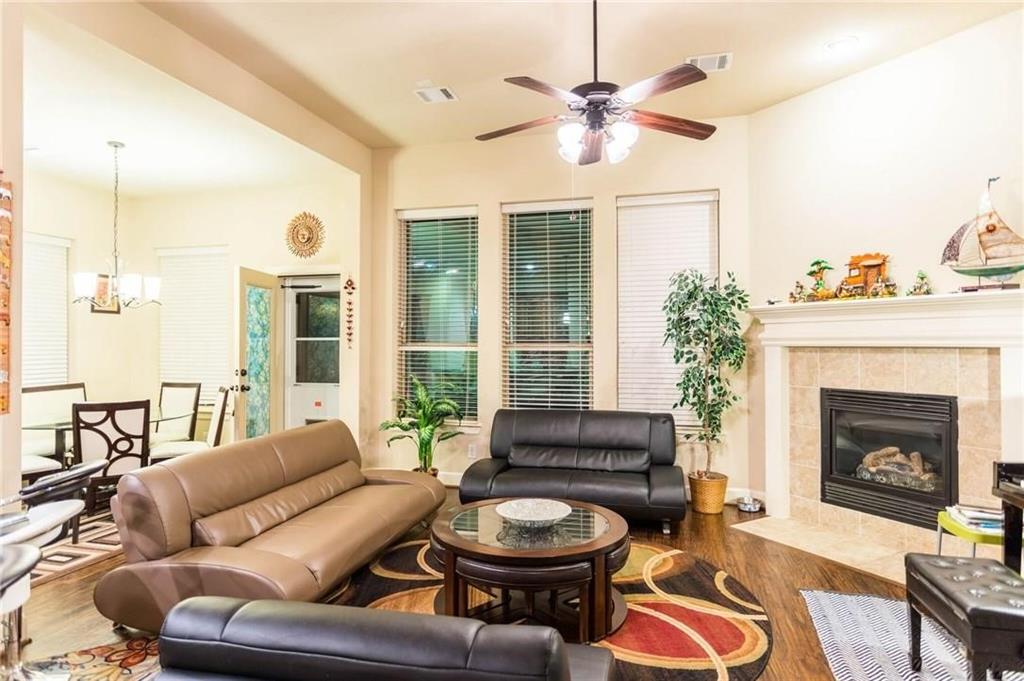 423 Palacio Street Irving, TX 75039 - Photo 14 of 18 Living area with wood finished floors, a chandelier, a tiled fireplace, and ceiling fan