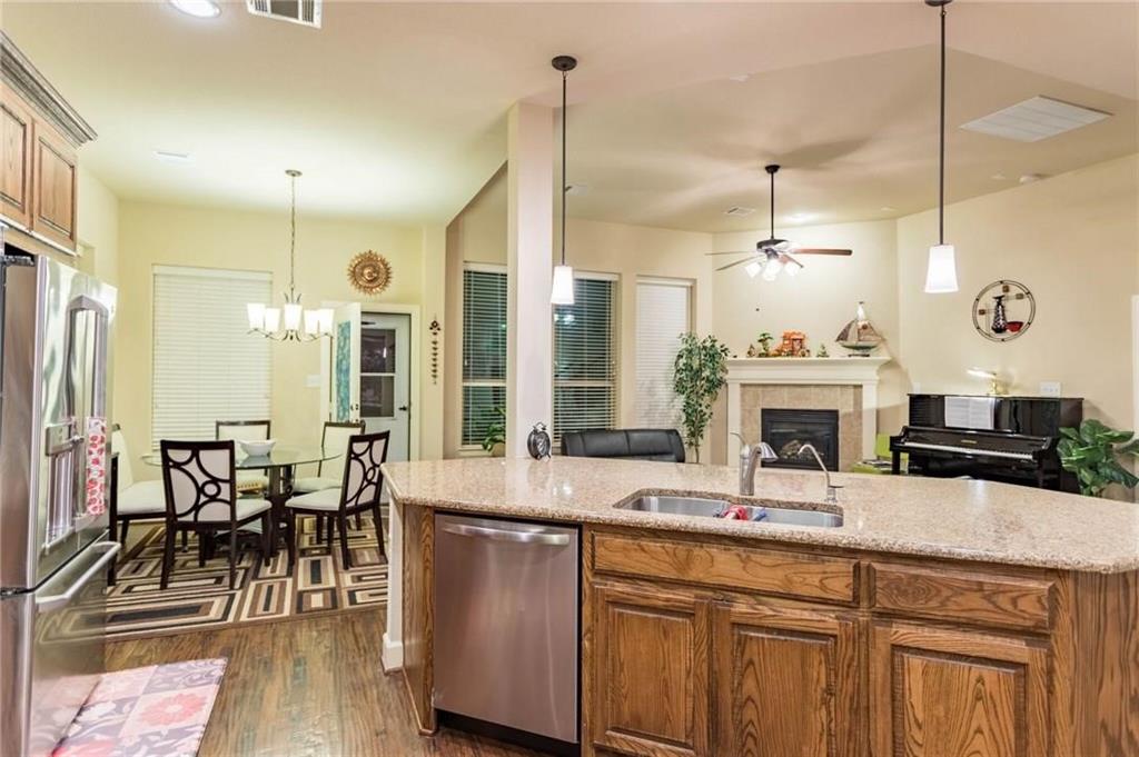 423 Palacio Street Irving, TX 75039 - Photo 17 of 18 Kitchen with brown cabinetry, decorative light fixtures, appliances with stainless steel finishes, a fireplace, and recessed lighting