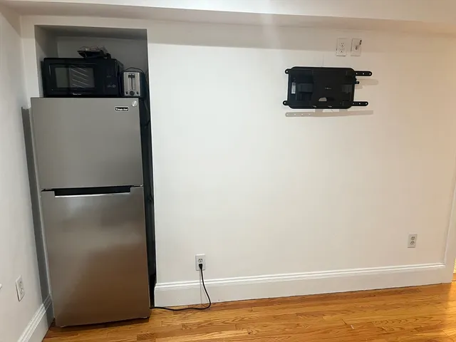 a view of a refrigerator in kitchen and an empty room