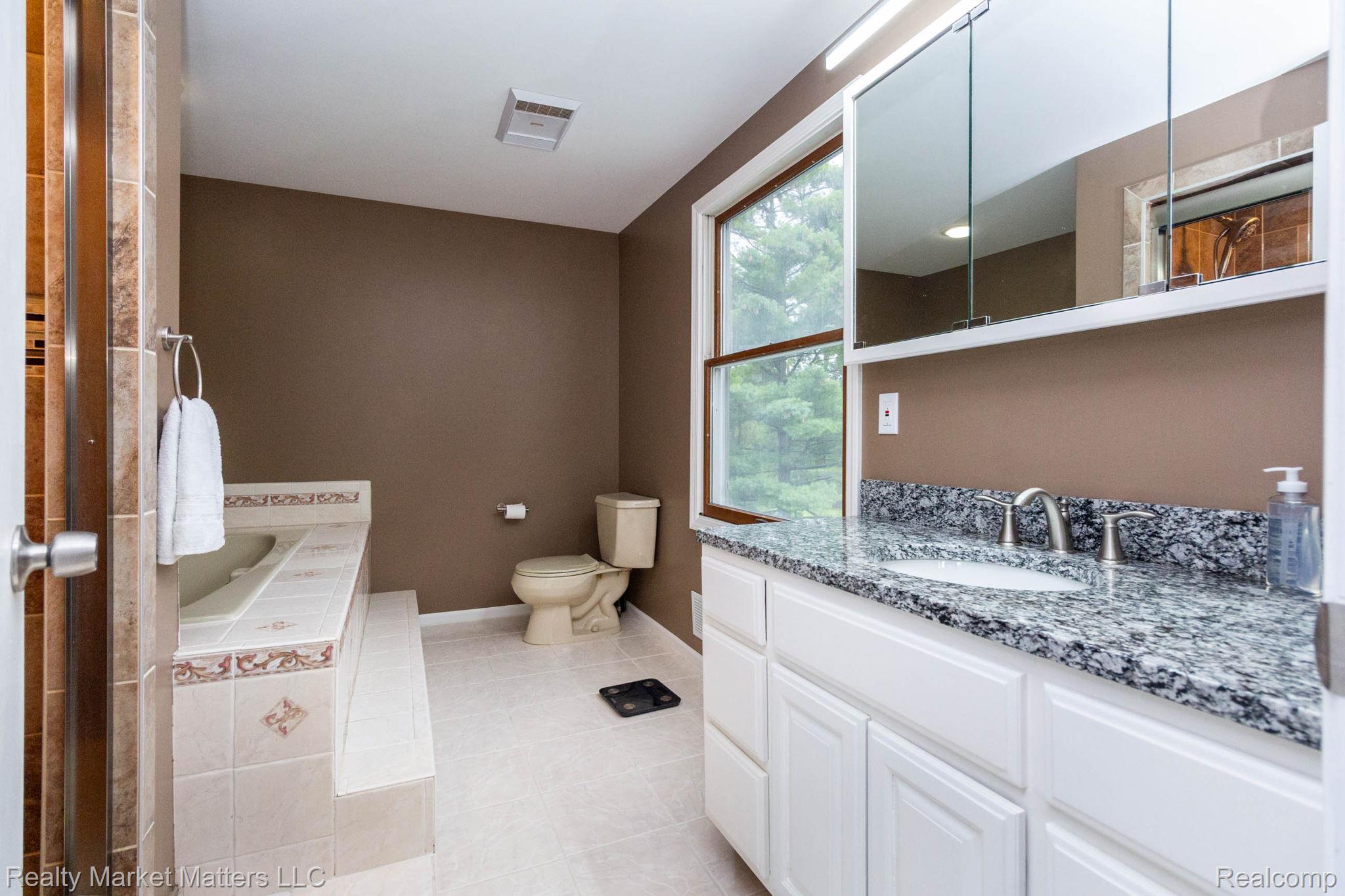 770 North Fairgrounds Road Imlay City, MI 48444 - Photo 15 of 55 Bathroom featuring a built-in tub with tiled surround, a vanity with a stone-finish countertop, white cabinetry, and an integrated sink