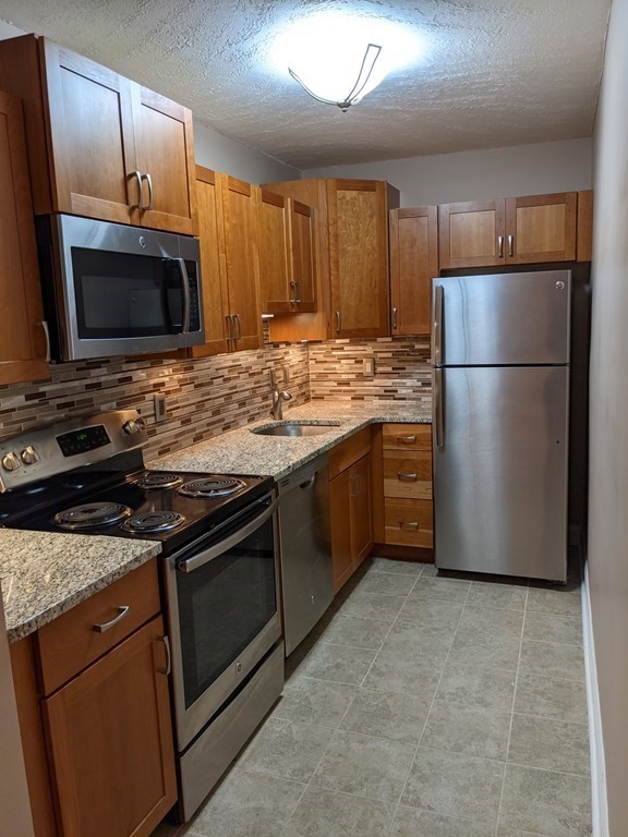 72 Leonard Road, Unit 72 Boxborough, MA 01719 - Photo 5 of 25 a kitchen with stainless steel appliances granite countertop a stove a refrigerator and a microwave